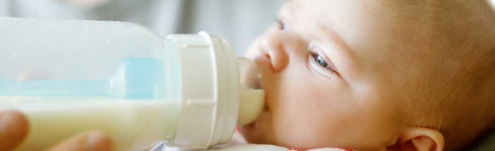 Milch wird für einen Säugling in einer Flasche als Zubehör für Babybedarf verabreicht
